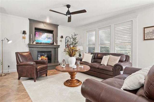 living room with light tile patterned flooring, ceiling fan, crown molding, and a tile fireplace