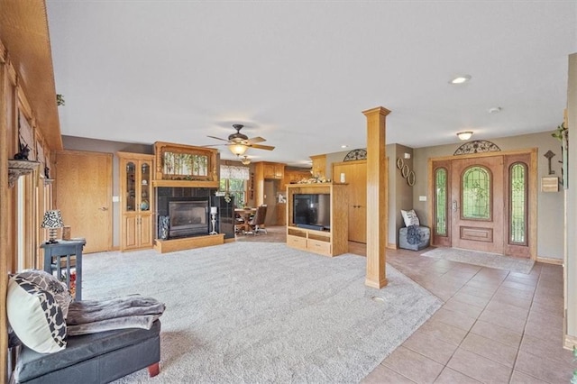 living room featuring a tiled fireplace, decorative columns, light tile patterned floors, and ceiling fan