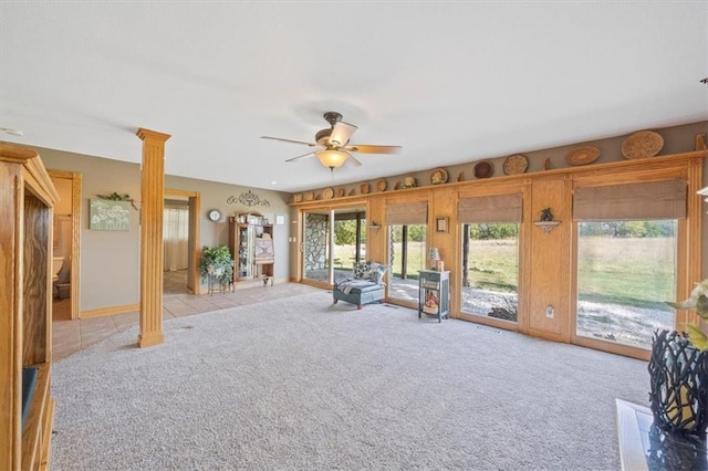 unfurnished living room with ornate columns, light carpet, and ceiling fan