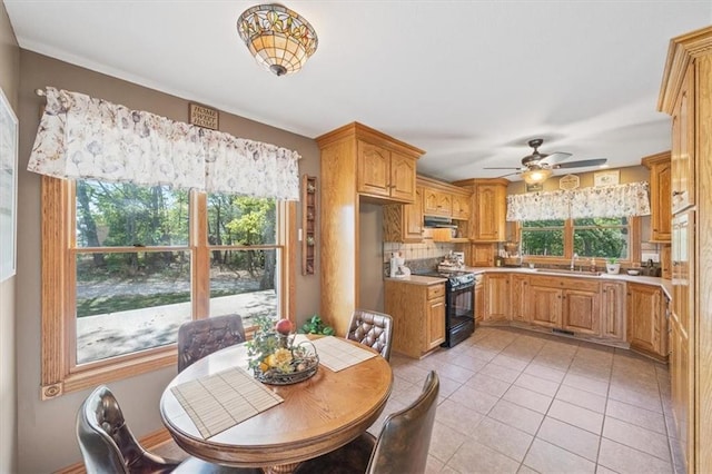 dining space with sink, light tile patterned floors, and ceiling fan