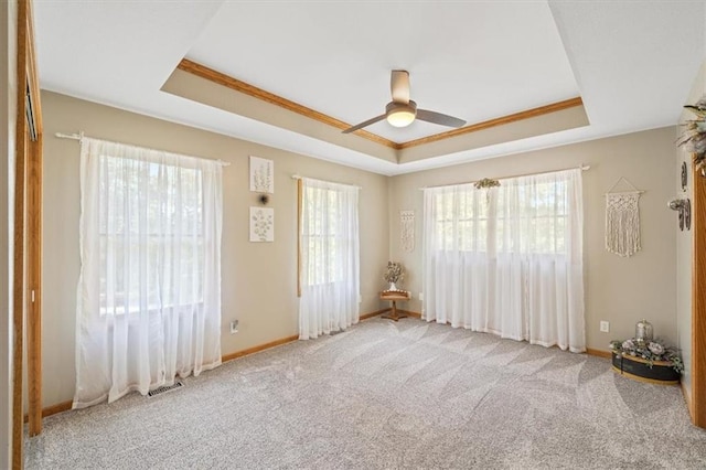 unfurnished room with crown molding, a tray ceiling, light colored carpet, and ceiling fan