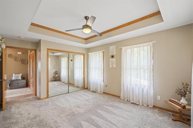 unfurnished bedroom with a raised ceiling, a closet, and ceiling fan