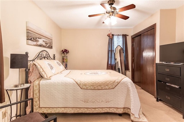 bedroom with ceiling fan, a closet, and light carpet