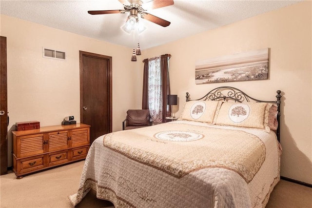 bedroom featuring ceiling fan, a textured ceiling, and light carpet