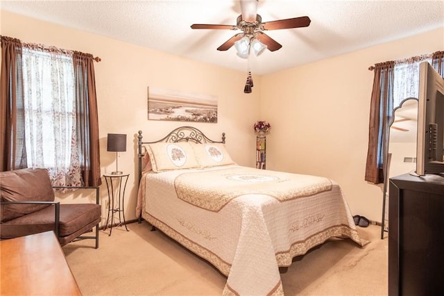 carpeted bedroom featuring multiple windows, ceiling fan, and a textured ceiling