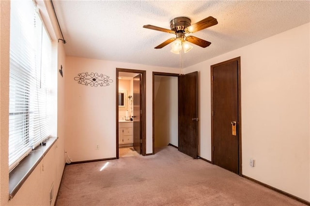 unfurnished bedroom with a textured ceiling, ceiling fan, connected bathroom, and light colored carpet