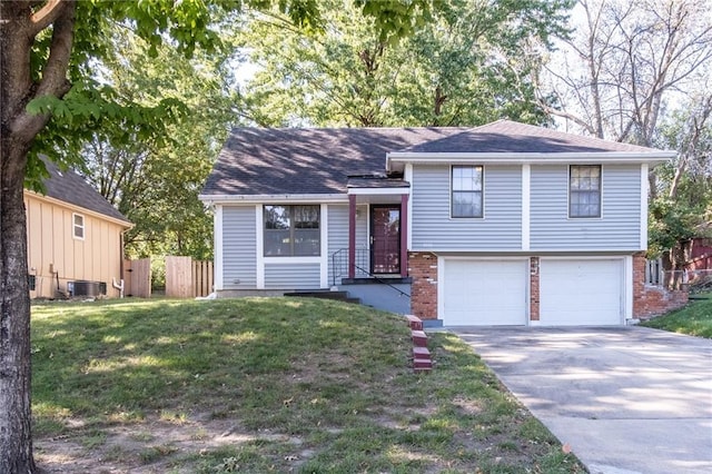 split level home with cooling unit, a garage, and a front lawn