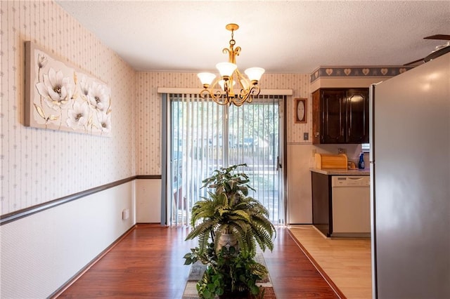 dining room featuring a textured ceiling, a chandelier, and dark hardwood / wood-style flooring