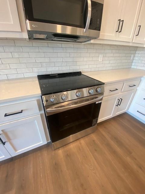 kitchen with appliances with stainless steel finishes, light countertops, white cabinetry, and dark wood-style floors