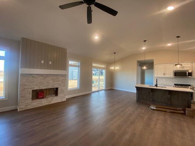 kitchen featuring open floor plan, dark wood-type flooring, stainless steel microwave, and a sink