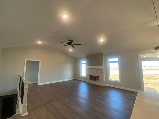 unfurnished living room with lofted ceiling, ceiling fan, a fireplace, baseboards, and dark wood finished floors