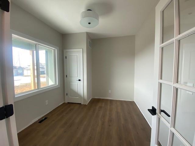 unfurnished bedroom with visible vents and wood finished floors