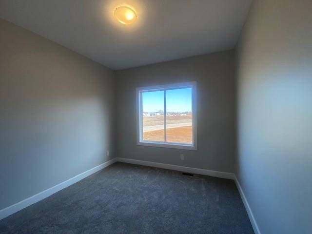 empty room with dark carpet and baseboards