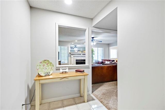 hall featuring a textured ceiling and light colored carpet