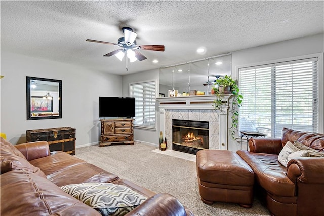 living room featuring ceiling fan, carpet, a textured ceiling, and a tile fireplace