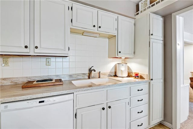 kitchen with light carpet, decorative backsplash, white cabinetry, white dishwasher, and sink