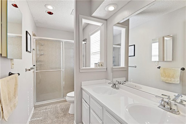 bathroom with vanity, a shower with shower door, a textured ceiling, and toilet