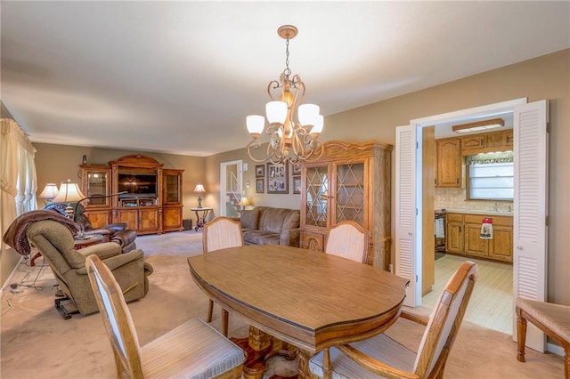 dining area with a notable chandelier, light colored carpet, and sink