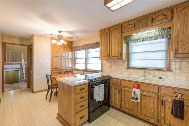 kitchen with black electric range oven, sink, ceiling fan, tasteful backsplash, and kitchen peninsula