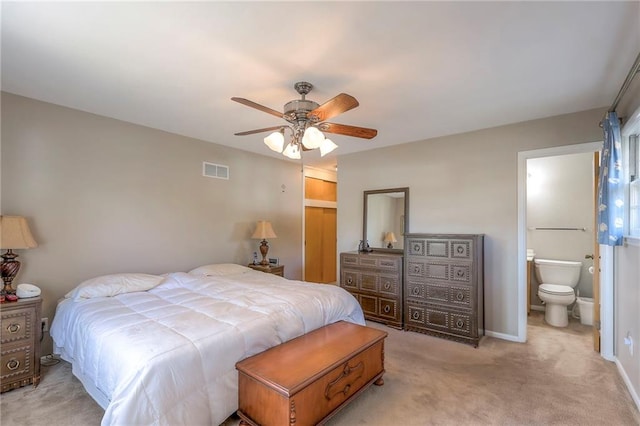 bedroom featuring ceiling fan, light colored carpet, and ensuite bathroom