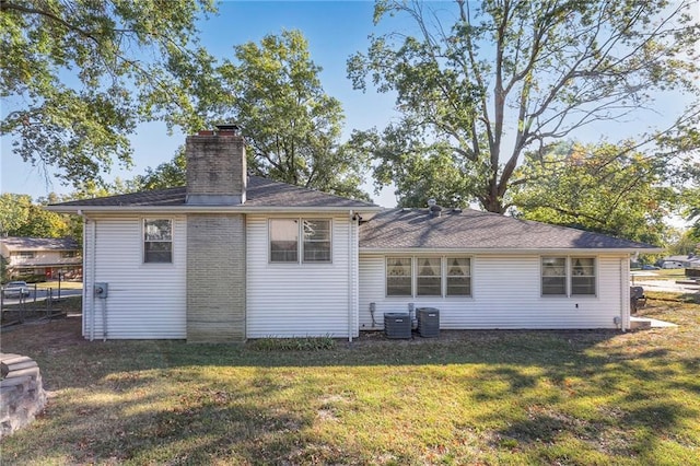 rear view of property featuring a yard and central AC unit