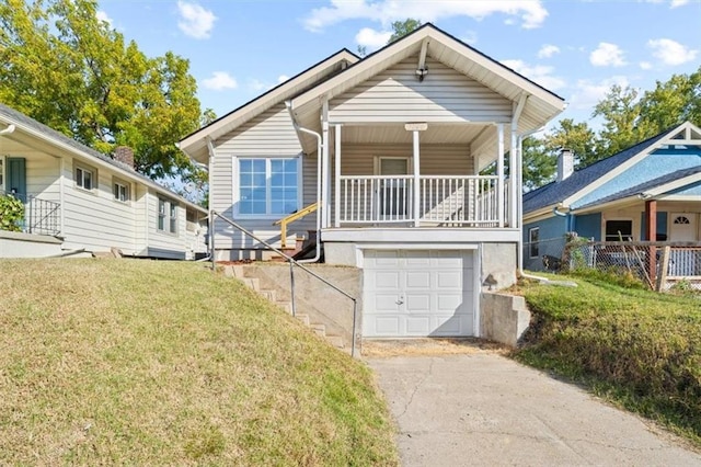 bungalow-style house with a front yard, a garage, and covered porch