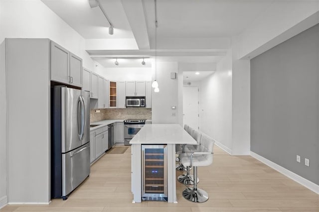 kitchen featuring stainless steel appliances, a kitchen island, light hardwood / wood-style flooring, decorative light fixtures, and wine cooler