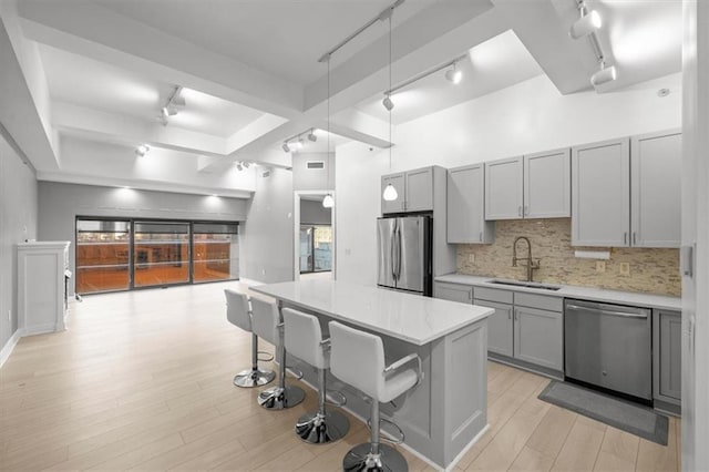1101 Walnut St Unit 605, Kansas City, MO 64106 - kitchen with appliances with stainless steel finishes, rail lighting, a sink, gray cabinetry, and a breakfast bar area