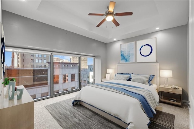 bedroom featuring a tray ceiling, carpet, and ceiling fan