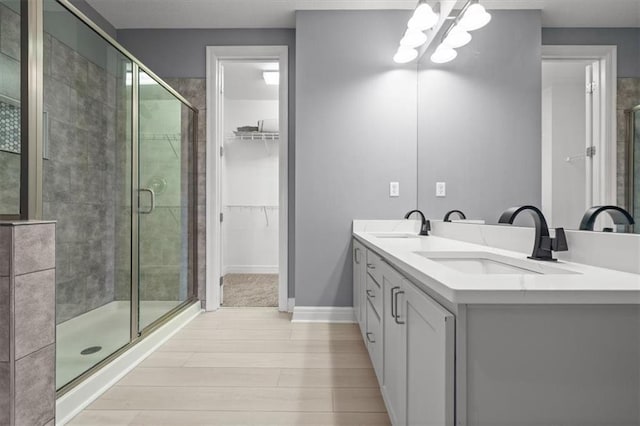 1101 Walnut St Unit 605, Kansas City, MO 64106 - full bathroom featuring wood finished floors, a shower stall, double vanity, a spacious closet, and a chandelier