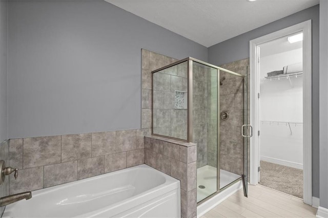 1101 Walnut St Unit 605, Kansas City, MO 64106 - full bathroom with a garden tub, a stall shower, a spacious closet, and wood finished floors