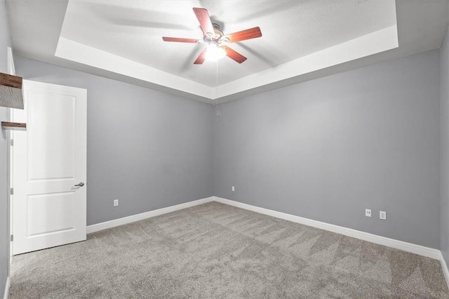 unfurnished room featuring carpet floors, ceiling fan, and a raised ceiling