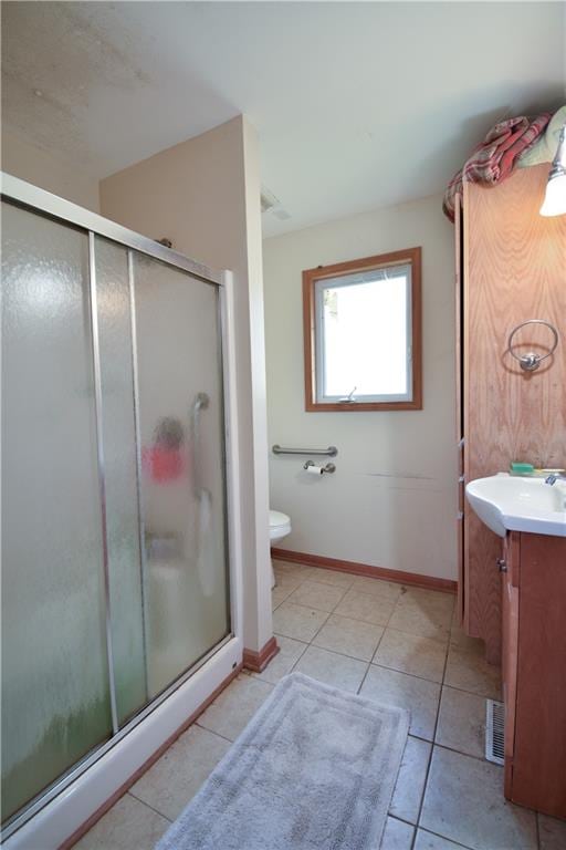 bathroom featuring vanity, toilet, a shower with shower door, and tile patterned flooring