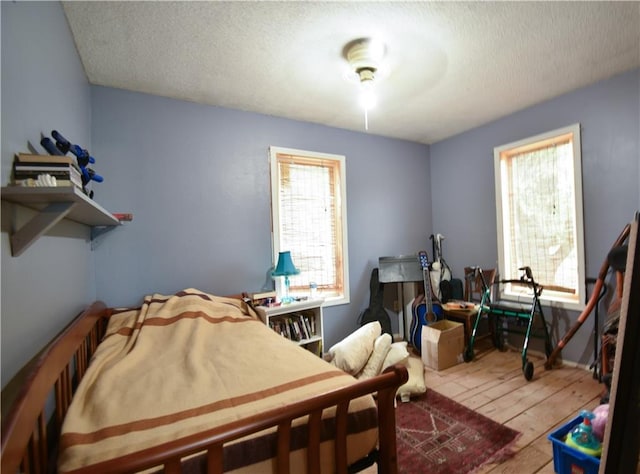 bedroom featuring hardwood / wood-style floors, a textured ceiling, and ceiling fan