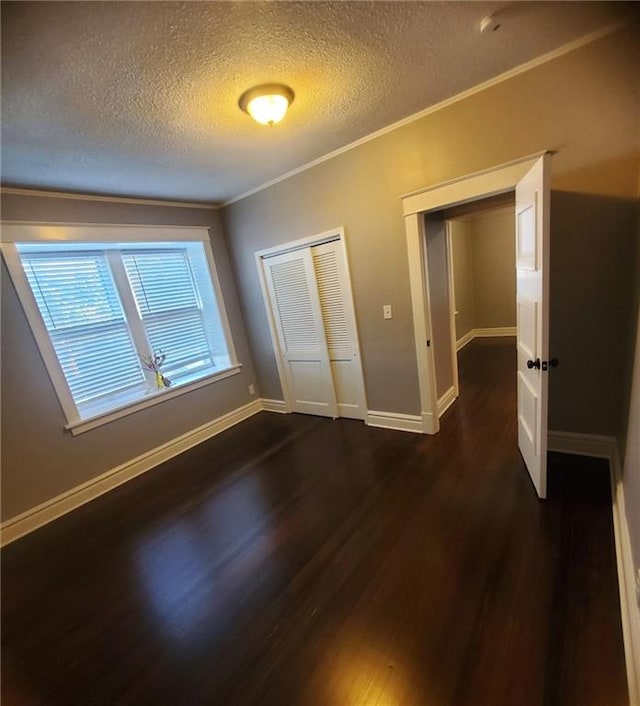 unfurnished bedroom with ornamental molding, a textured ceiling, a closet, and dark hardwood / wood-style flooring