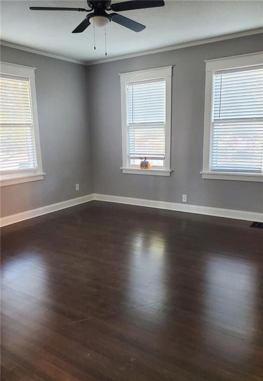 empty room with crown molding, a healthy amount of sunlight, ceiling fan, and dark hardwood / wood-style flooring