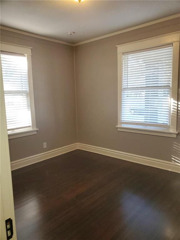 unfurnished room featuring ornamental molding, dark wood-type flooring, and plenty of natural light