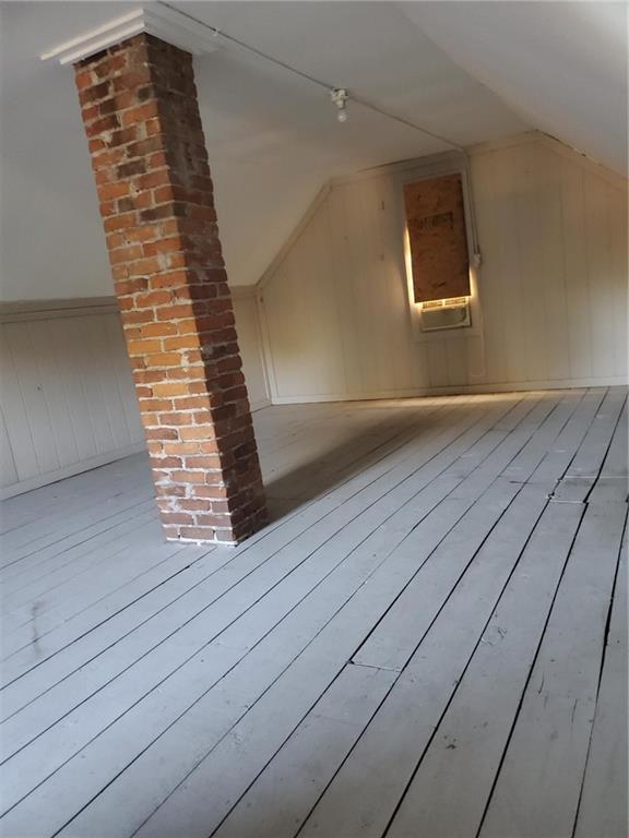 bonus room featuring lofted ceiling, wooden walls, and light hardwood / wood-style floors