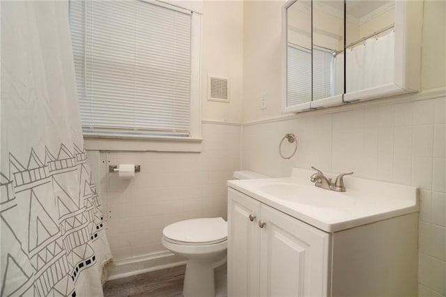 bathroom with vanity, toilet, wood-type flooring, and tile walls