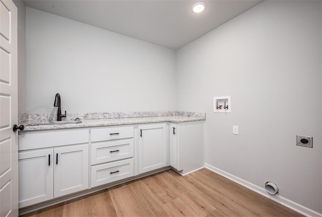 clothes washing area featuring electric dryer hookup, cabinets, sink, washer hookup, and light hardwood / wood-style floors