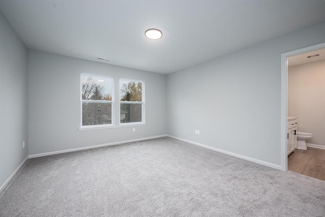 unfurnished bedroom with connected bathroom and carpet floors