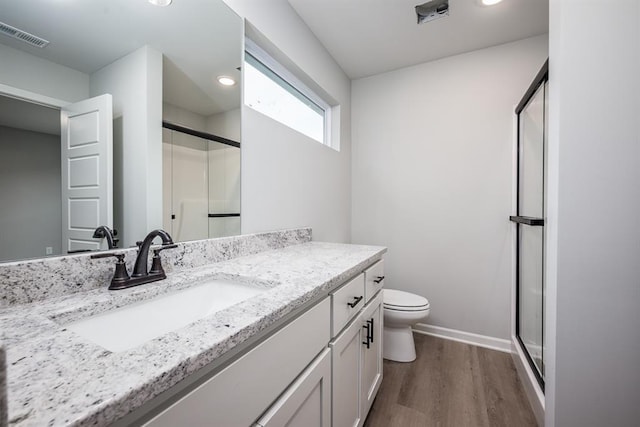 bathroom featuring vanity, hardwood / wood-style flooring, toilet, and a shower with shower door