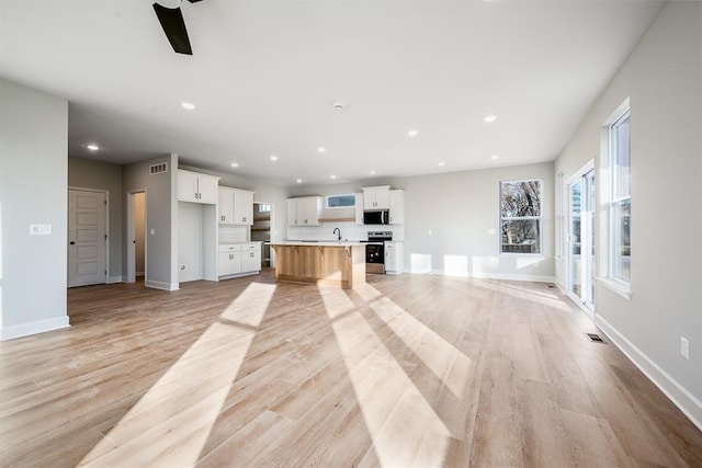 unfurnished living room with ceiling fan and light hardwood / wood-style flooring