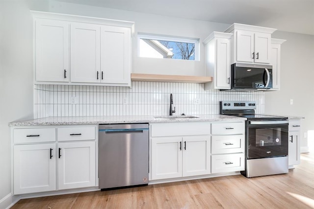 kitchen with sink, light wood-type flooring, tasteful backsplash, white cabinetry, and stainless steel appliances