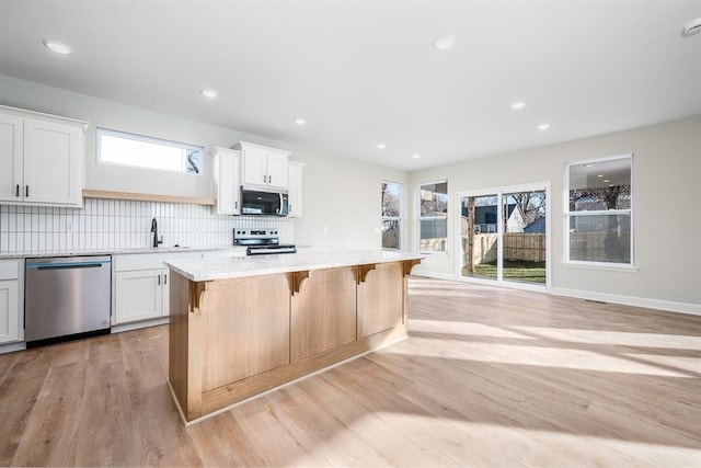 kitchen featuring white cabinets, a kitchen island, stainless steel appliances, and a wealth of natural light