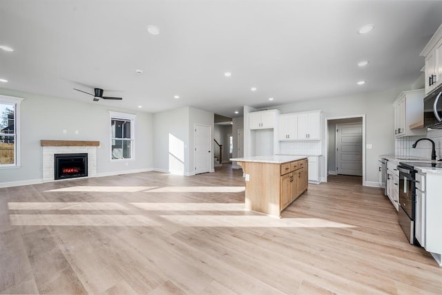 kitchen featuring white cabinetry, a kitchen island, stainless steel electric stove, and light hardwood / wood-style floors