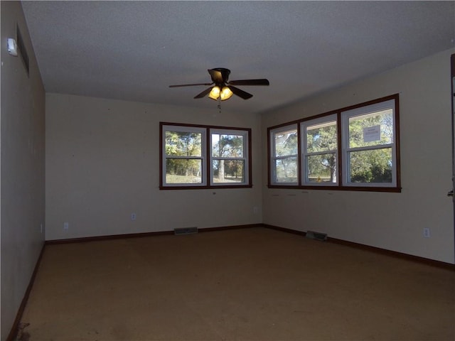 unfurnished room featuring light colored carpet, a textured ceiling, a healthy amount of sunlight, and ceiling fan