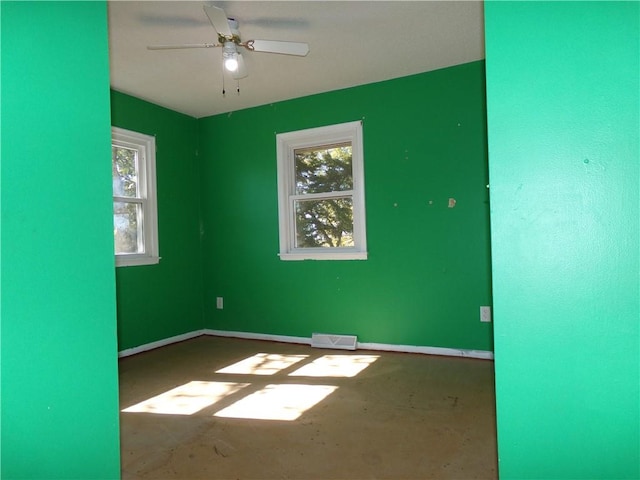 unfurnished room with ceiling fan, concrete flooring, and a wealth of natural light