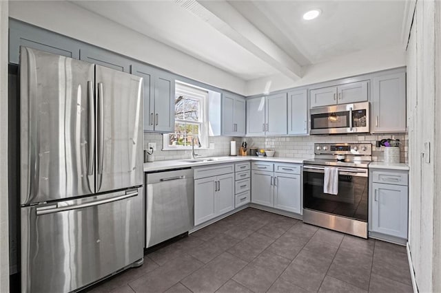 kitchen with decorative backsplash, sink, beamed ceiling, and stainless steel appliances