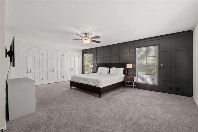 bedroom featuring ceiling fan, carpet floors, and two closets